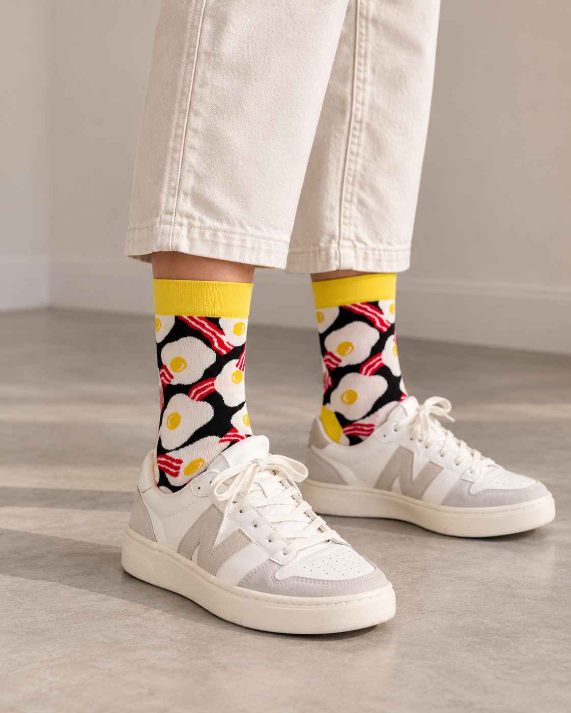 Happy Socks γυναικείες κάλτσες Egg & Bacon με τηγανητά αυγά, κόκκινες λωρίδες μπέικον και κίτρινο τελείωμα, φορεμένες.