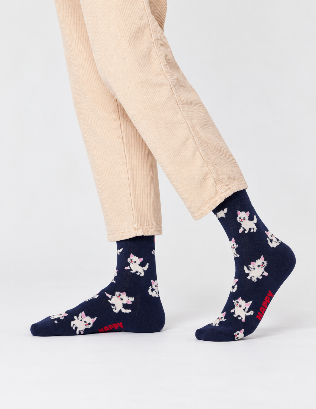 Happy Socks γυναικείες σκούρες μπλε κάλτσες Kitten με λευκά γατάκια, ροζ λεπτομέρειες και κόκκινο λογότυπο, φορεμένες.