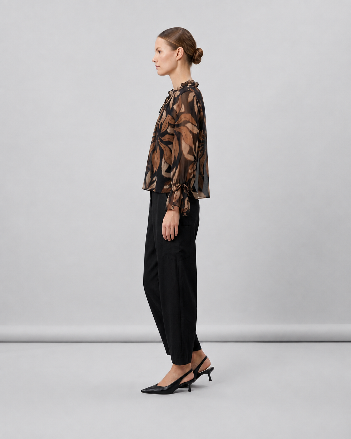 Γυναικεία μαύρη floral μπλούζα georgette με αέρινα μανίκια και σούρες, πλάγια εμφάνιση με μαύρο παντελόνι
