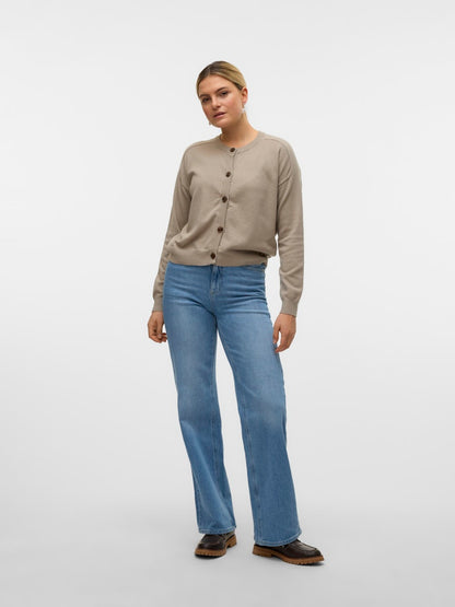 Μοντέλο που φοράει τη μπεζ πλεκτή ζακέτα VERO MODA με τζιν παντελόνι, ολόσωμη λήψη