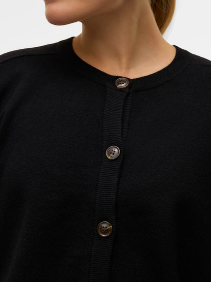 Κοντινή λήψη της στρογγυλής λαιμόκοψης και των διακοσμητικών κουμπιών της μαύρης ζακέτας VERO MODA