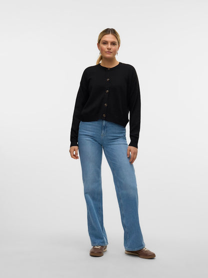 Μοντέλο που φοράει τη μαύρη πλεκτή ζακέτα VERO MODA με τζιν παντελόνι, ολόσωμη λήψη